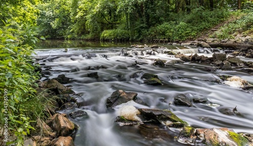 rzeka, woda rozmyty ruch wody między kamieniami, w tle las