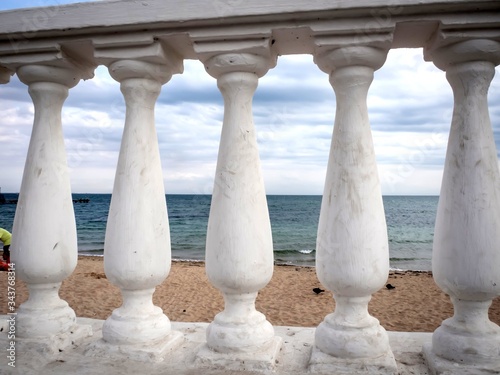 A balustrade, consisting of a series of curly columns, protects the seashore.