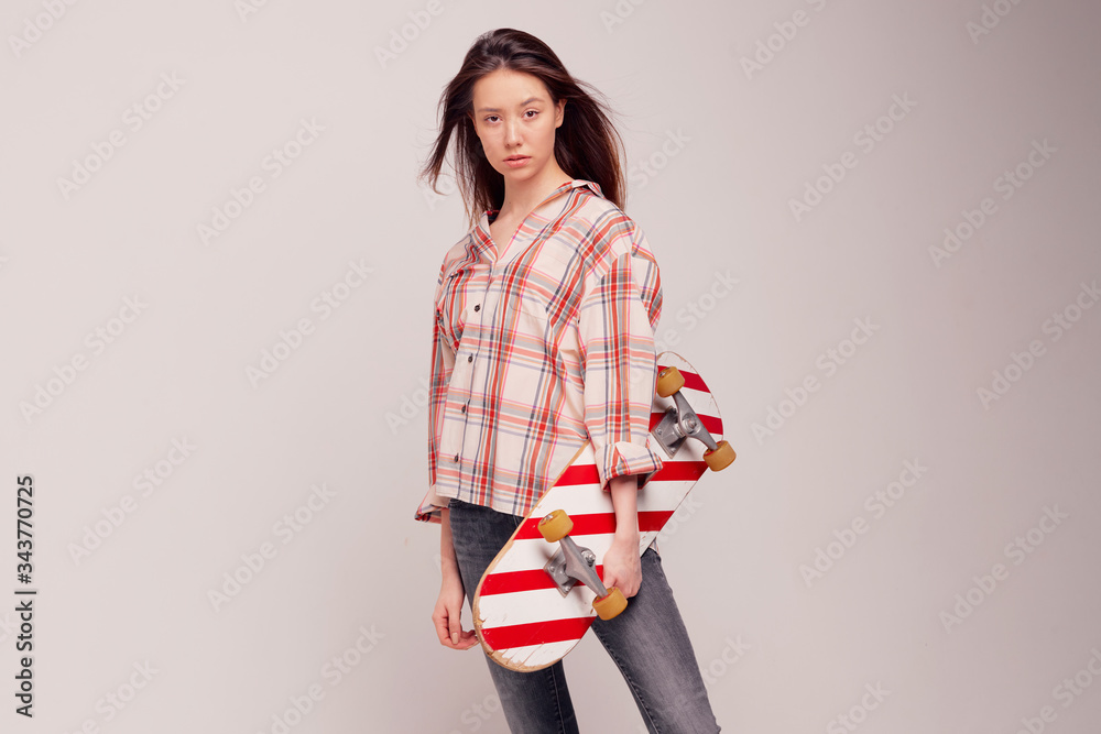 Cool girl student in casual clothes learns to ride a skateboard after classes at the University. Cool girl student in casual clothes learns to ride a skateboard after classes at the University.