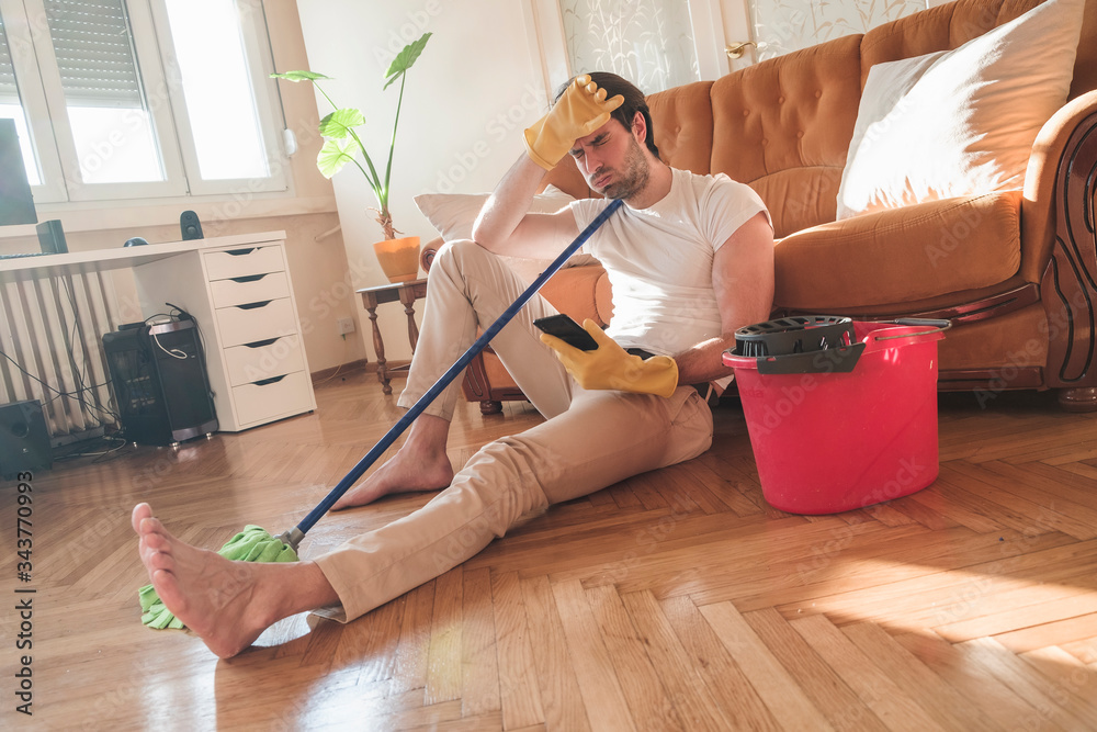 © Teodor Lazarev - Handsome man cleaning his house with mop and plastic bucket, he working hard
