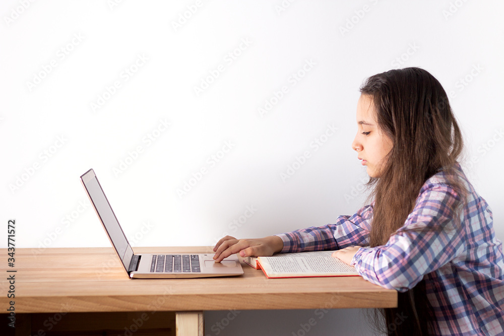 Distance learning at home. Teen girl with laptop does homework, reads a book, search information on the Internet. Elearning concept. Distance learning at home. Teen girl with laptop does homework, reads a book, search information on the Internet. Elearning concept.