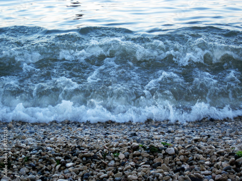 Coastal sea waves run onto stones lying on the shore .                     