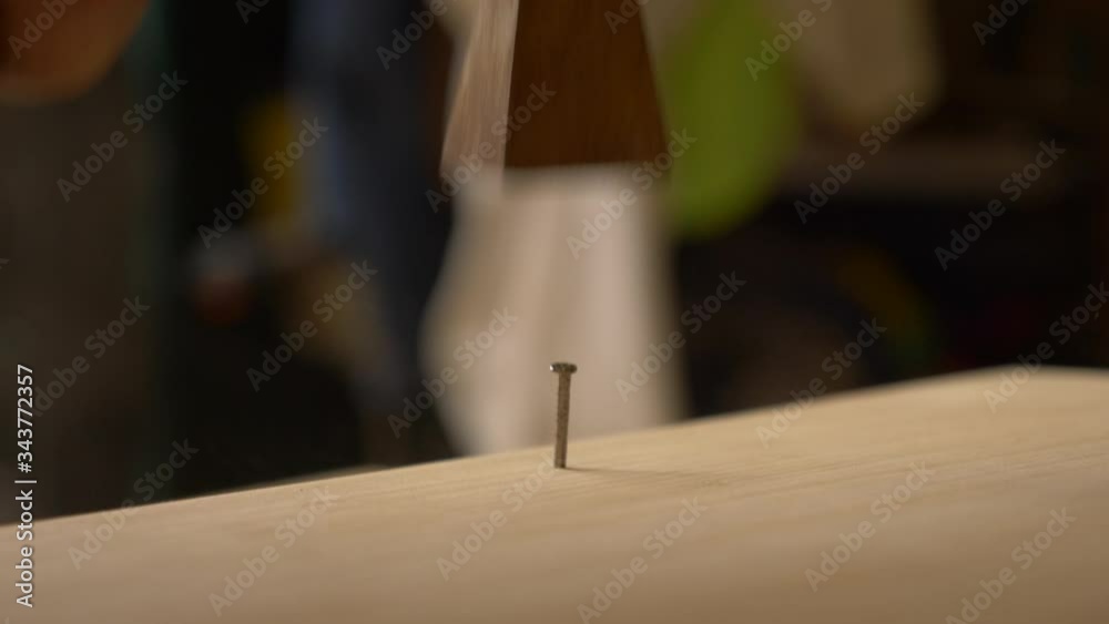 Macro, martillo clavando un clavo en en una tabla en un taller de carpintería artesanal