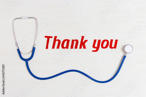 Healthcare and medical concept. Stethoscope blue colored and text "thank you" on white wooden background with copy space. National Nurses Day. Top view.