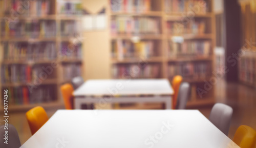 Empty White wooden table  ready for your product display montage. with book shelf in library blurred background. Blurry perspective view of educational study room space with book shelves.