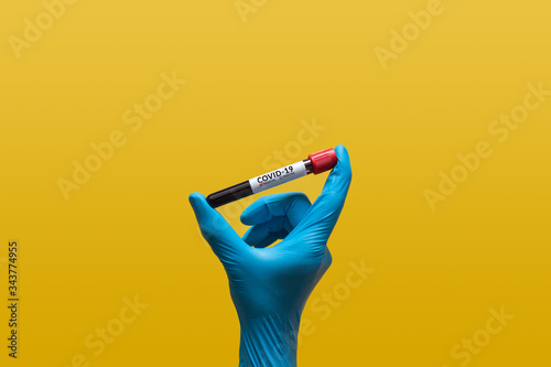 hand in blue rubber glove holding Coronavirus blood sample in test tube for covid-19 analyzing with negative results. laboratory analyzing for testing and invent drug and vaccine for Coronavirus