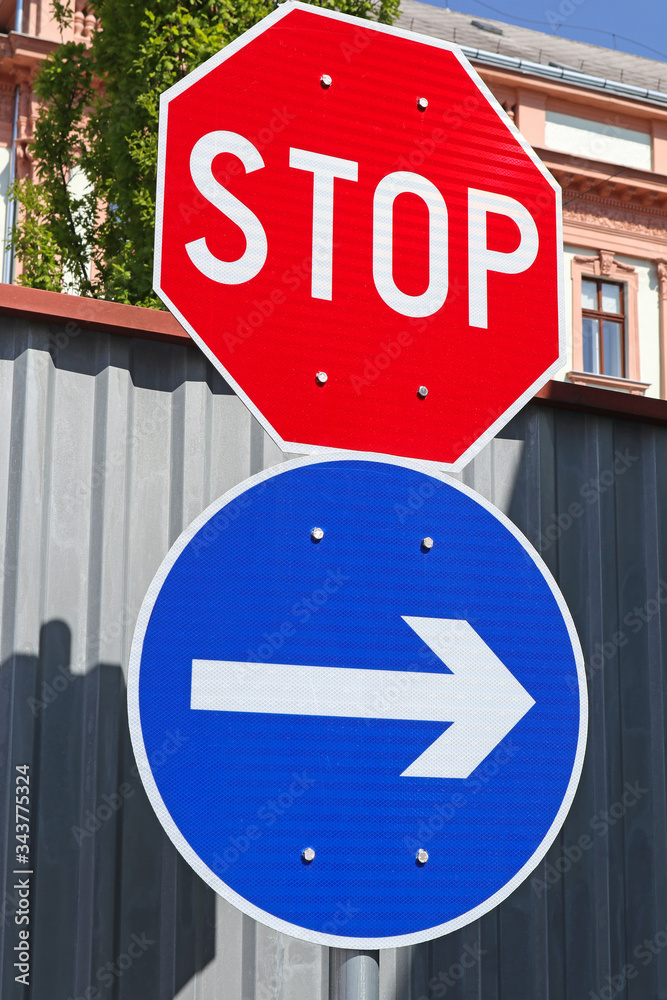 Stop sign and arrow sign at the road crossing