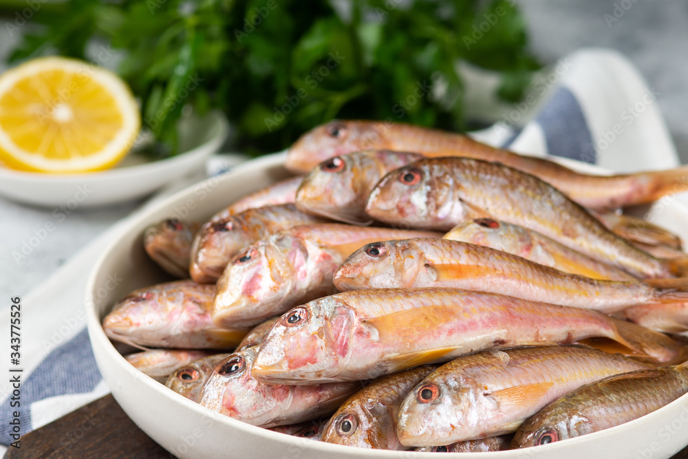 Black sea barabulka fish in a white ceramic bowl on a light gray kitchen table. A lot of fish red mullet. Black sea barabulka