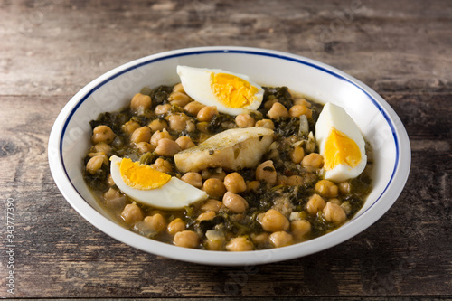 Chickpea stew with spinach and cod or potaje de vigilia on wooden table
