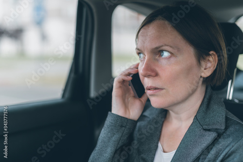 Businesswoman talking on mobile phone on car back seat © Bits and Splits