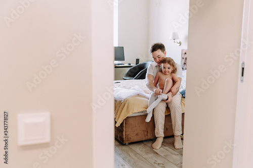 dad dresses his little daughter at home