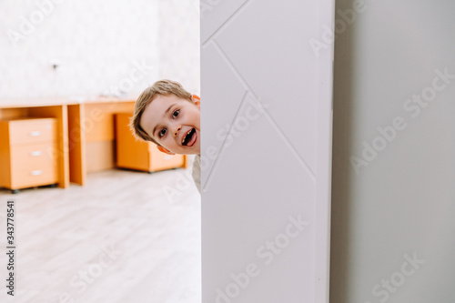 the boy peeks playfully around the corner