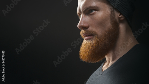 Silhouette of young confident handsome bearded man hipster wearing black knit hat. Handsome young bearded man in black t-shirt