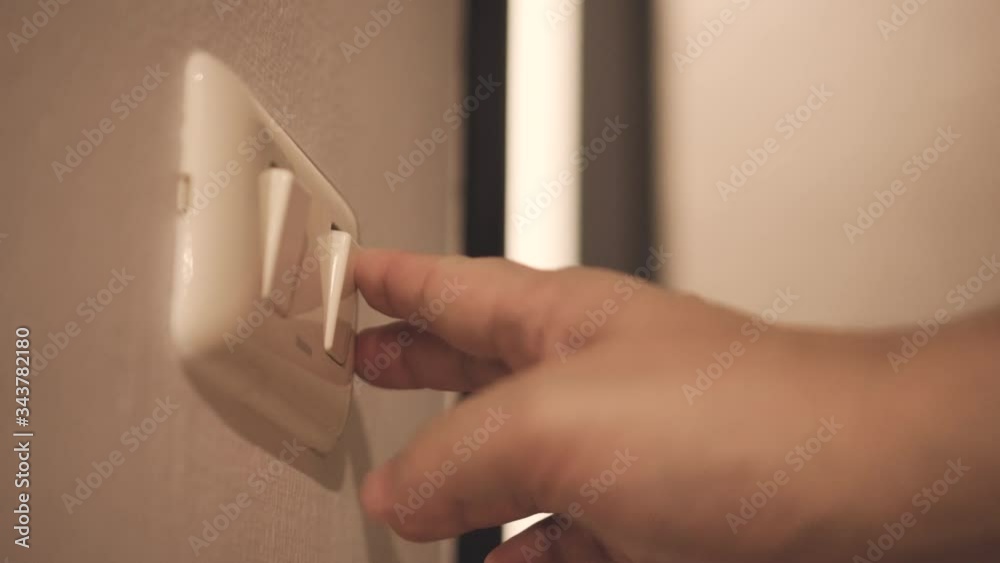 Close up hand switch on and off electric light . Concept of energy and power saving.