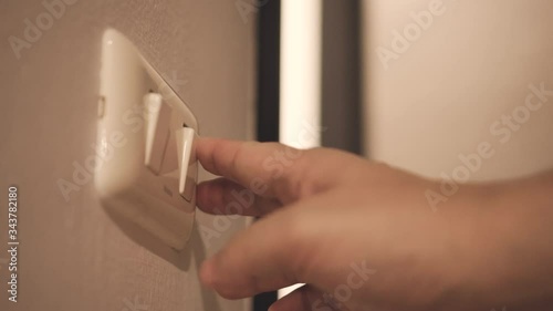 Close up hand switch on and off electric light . Concept of energy and power saving.