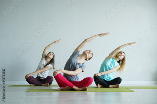 Three beautiful woman doing yoga practice indoors