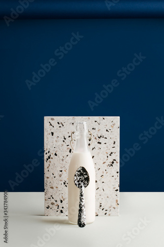 Milk bottle and spoon with tile on table