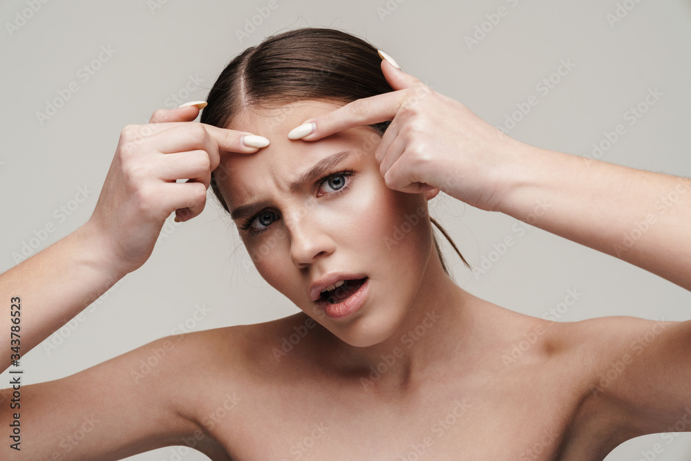 Image of displeased shirtless woman with acne touching her forehead