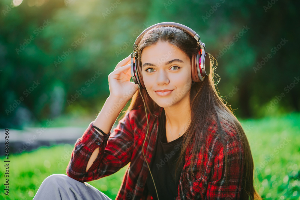 Portrait of attractive girl dancing with earphones in park. Woman smiling. moves to the rhythm.Friendly appearance of modern trendy hipster Portrait of attractive girl dancing with earphones in park. Woman smiling. moves to the rhythm.Friendly appearance of modern trendy hipster