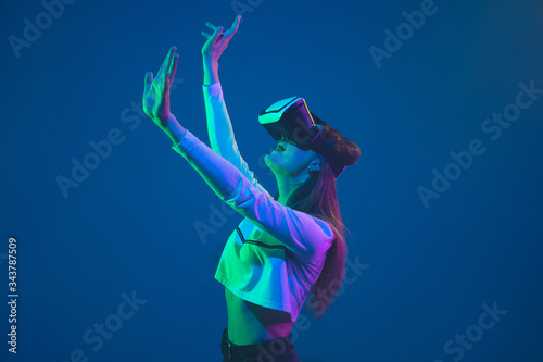 Playing in action. Caucasian young woman's portrait isolated on blue studio background in neon light. Beautiful female model. Concept of human emotions, facial expression, sales, ad, youth culture. photo