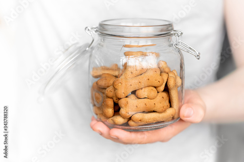 Photographie man holds dog cookies in the jar on a light background