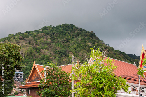 Roofs of houses on a background of green mountains and cloudy sky