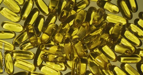 Stacked up vitamin supplement cod liver oil capsules reflect light. photo