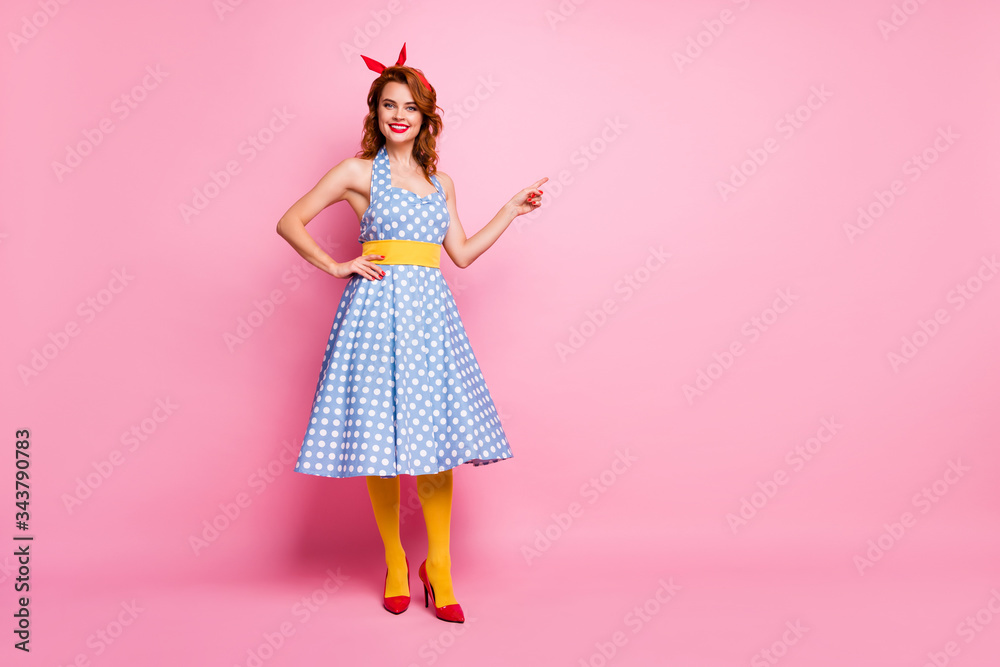 Full length photo of positive cheerful lady promoter point index finger copy space recommend choose decide ads promo wear blue stockings isolated over pink color background