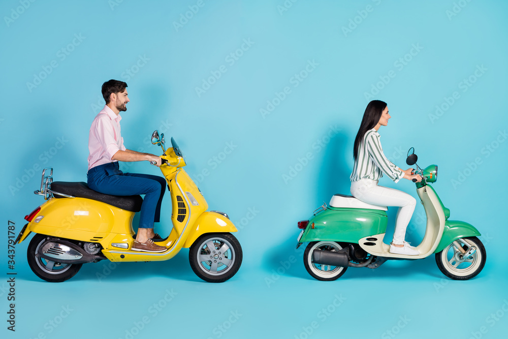 Full size profile side photo of positive cheerful man girl drive yellow green chopper enjoy freedom journey wear white striped shirt pants trousers pink isolated over blue color background Full size profile side photo of positive cheerful man girl drive yellow green chopper enjoy freedom journey wear white striped shirt pants trousers pink isolated over blue color background