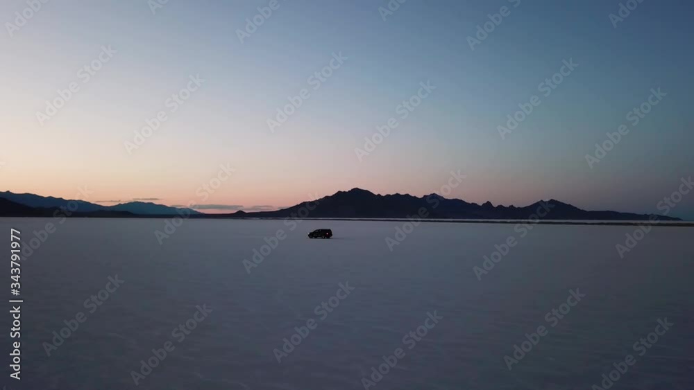 Orbit shot of SUV driving across Bonneville Salt Flats, USA at sunset Orbit shot of SUV driving across Bonneville Salt Flats, USA at sunset