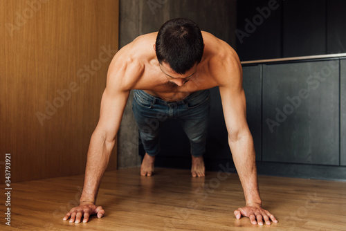 muscular man doing plank exercise at home