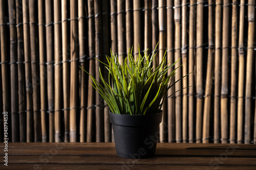 black plastic pot with artificial green grass on a beautiful background. plants for the office. interior decoration