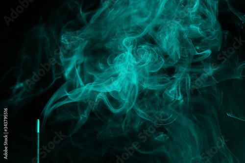 incense smoke. smoldering piece of wood . incense sticks in blue lighting. aromatic smoke . Green colour.