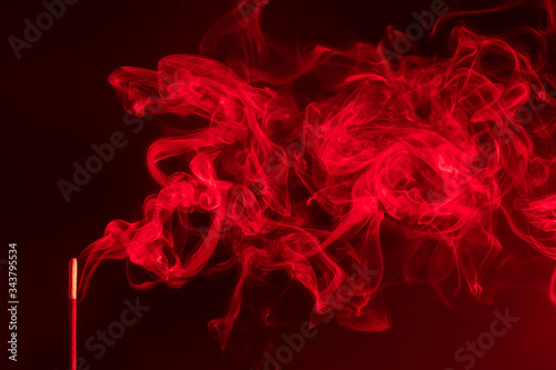 incense smoke. smoldering piece of wood . incense sticks in blue lighting. aromatic smoke . Red colour.