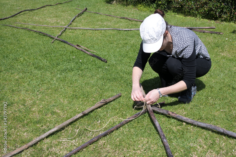 Young Woman Tying Knots Pieces of Wooden Poles Young Woman Tying Knots Pieces of Wooden Poles