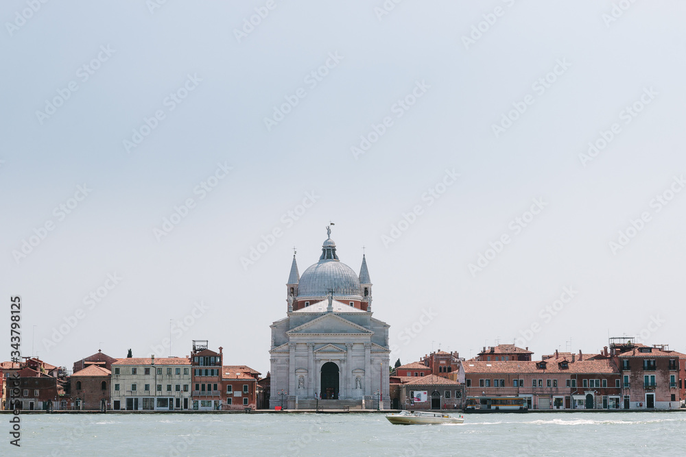 Street of Venice in summer time. Italian view. Roof, sea canal in sunny day. Old city, ancient buildings. Italy. Popular tourist destination of Italy. Europe. Church of the savior. Chiesa di Redentore