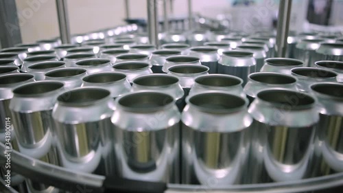 Technological line for bottling of beer in brewery. Empty aluminum beer cans are moving along the conveyor belt. Clean beer bottles are moving along the conveyor.Industry, production line, close up.