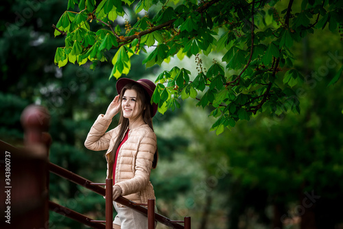 happy girl in a hat stands near a green chestnut tree in spring