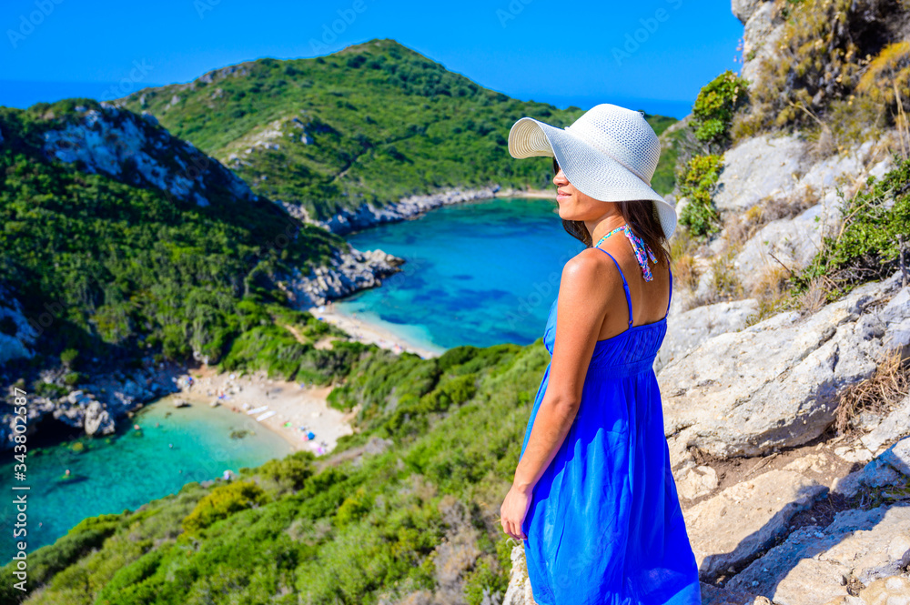 Girl with sun hat at Porto Timoni beach at Afionas is a paradise double beach with crystal clear azure water in Corfu, Ionian island, Greece, Europe