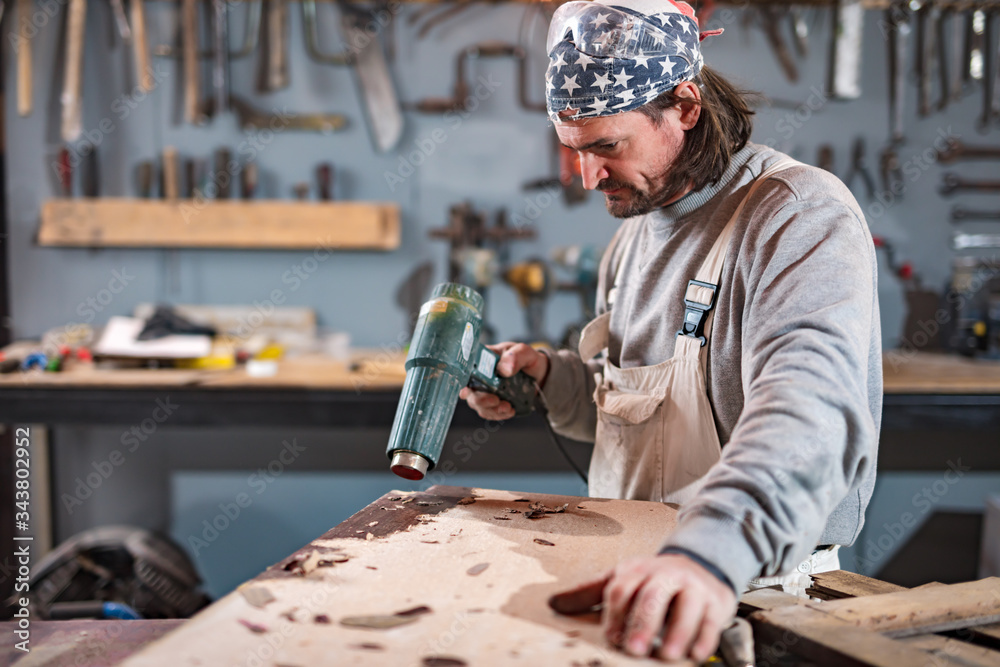 Fototapeta premium Male carpenter working on old wood in a retro vintage workshop.