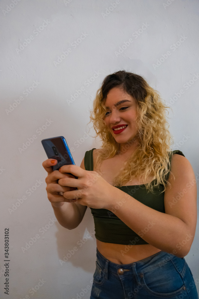 Young woman smiling and texting on her cell phone. Latin Caucasian model girl Young woman smiling and texting on her cell phone. Latin Caucasian model girl