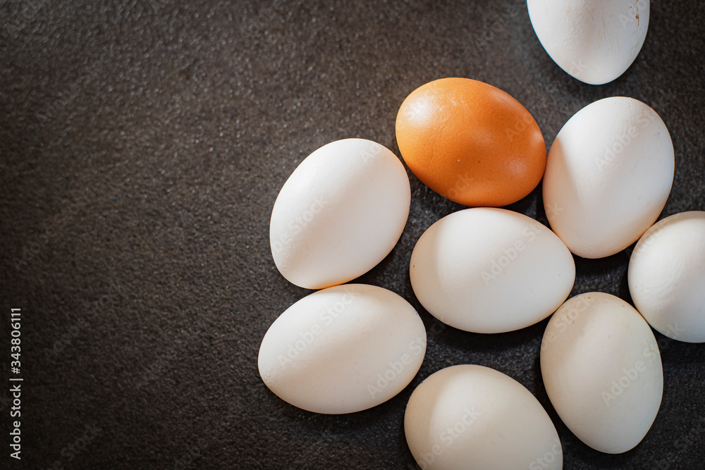 White eggs and brown eggs on a black background. Eggs on table. White eggs and brown eggs on a black background. Eggs on table.
