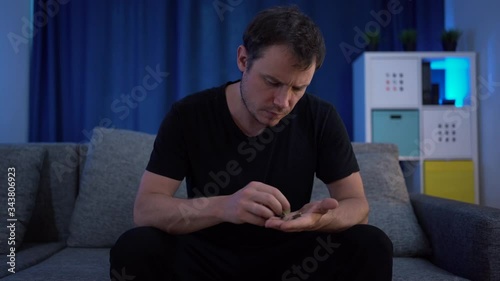a man sitting counting money on the sofa, very few of them