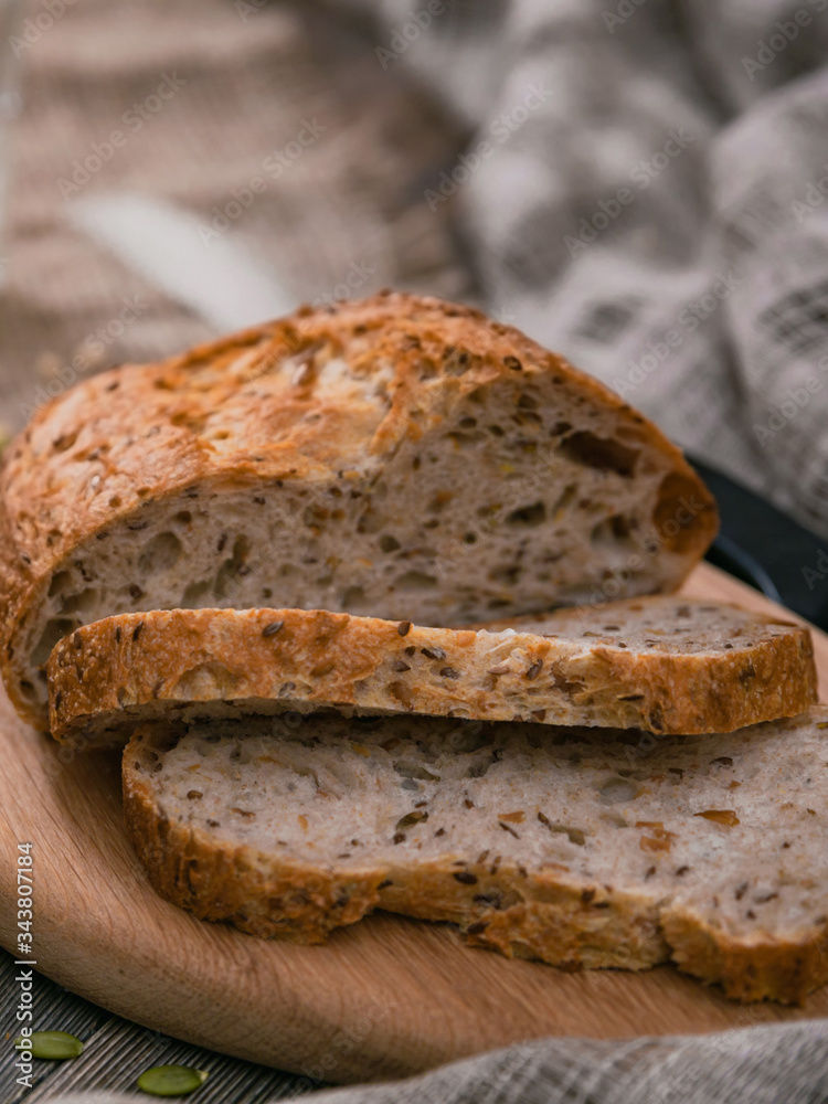 Sliced whole wheat bread on wooden board on planked table. Vertical shot from above.