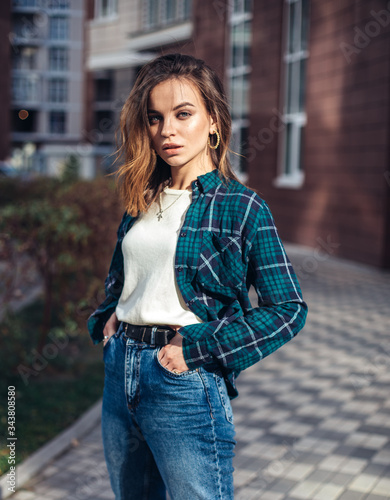 Fashion hipster woman posing outdoor. plaid shirt, fashionable high-waisted jeans,brunette hair.Trendy fashion style
