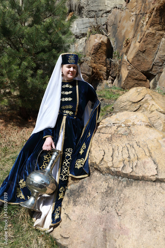 Woman posing with jug in traditional Karachai clothes photo