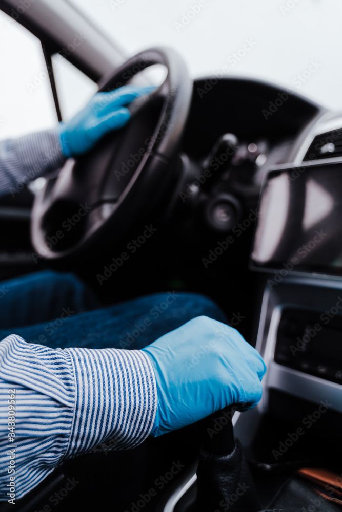 unrecognizable man driving a car wearing protective mask and gloves during pandemic coronacirus covid-19