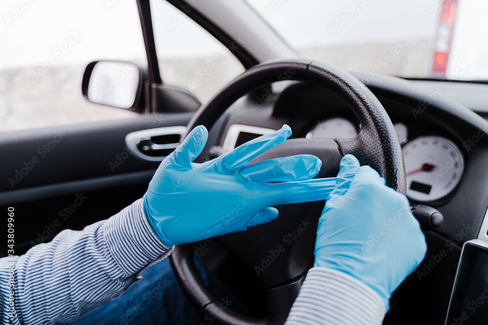 man in a car putting on protective mask and gloves during pandemic coronacirus covid-19