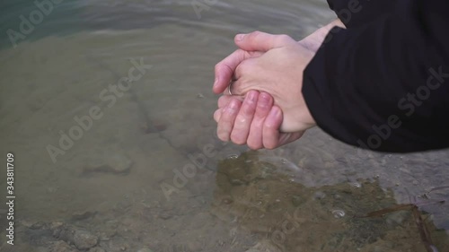 Las manos de una chica joven cogen agua de un lago. photo