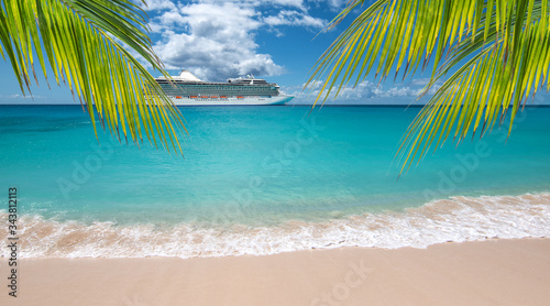 Tropical beach with palm trees. Side view of luxury cruise ship in the background.